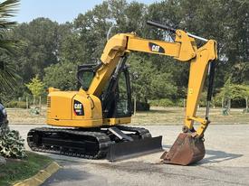 A yellow 2018 Caterpillar 308E2 excavator with a prominent digging arm and bucket positioned in a stationary stance