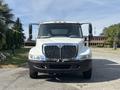 A white 2006 International 4300 truck facing forward with a chrome grille and multiple front lights