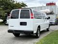 A white 2021 Chevrolet Express van viewed from the rear with tinted windows and chrome wheels