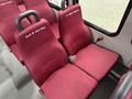 Interior seating of a 2017 Ford E450 bus featuring red fabric seats with personalized labels for passengers