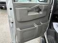 A close-up view of the driver-side door panel of a 2023 GMC Savana featuring storage compartments and a door handle