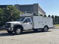 A 2011 Ford F-550 truck with a white exterior and utility body featuring multiple storage compartments and tools mounted on the bed