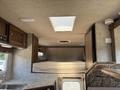 Interior view of a 2018 Westland Travelaire featuring a bed above a countertop and window with light streaming in from a ceiling vent