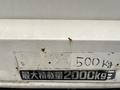 A close-up view of a white truck with rust spots showing a faded weight capacity label indicating a maximum load of 2000 kg and another label showing 500 kg