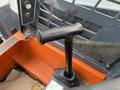 Close-up of the control lever of a 2017 Gehl R105 skid steer loader with a black handle and an orange base