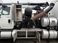 A 2013 International Workstar 7500 with a black engine, silver storage compartment, and large exhaust pipe on the side