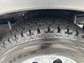 Close-up of a rugged tire with deep treads mounted on a silver wheel featuring the word Wrangler on the sidewall