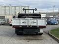 A 2015 Ford F-350 truck with a flatbed and visible tailgate features including lights and a hitch at the rear