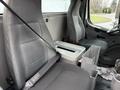 Interior of a 2005 Freightliner M2 106 featuring two gray fabric seats with seatbelts a central console and metal storage compartments between the seats