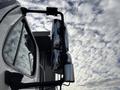 A 2013 Freightliner 114SD truck with a prominent side mirror reflecting the sky and clouds