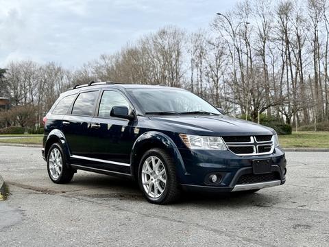 A blue 2013 Dodge Journey with silver alloy wheels parked at an intersection showcasing its sleek design and spacious SUV features