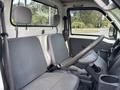 Interior view of a 2010 Daihatsu Hijet showing two gray seats and a steering wheel with a simple dashboard and controls