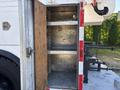 An open storage compartment of a 2006 Freightliner M2 106 showing two metal shelves with an empty interior