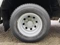 A close-up of a silver wheel for a 2012 Ford Econoline featuring a central hub and multiple lug nut openings with a black tire mounted on it
