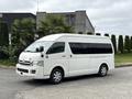 A white 2009 Toyota Hiace van with tinted windows and a side door for passenger access parked at an angle