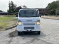 A white 2008 Suzuki Carry van facing forward with its headlights on showcasing its distinctive front grille and compact design