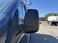 A close-up view of the side mirror of a blue 2016 Ford Transit 150 showing the mirror's structure and design