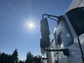 A 2013 International 7500 truck with a large side mirror positioned prominently against a bright sunlit sky