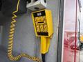 A yellow control panel with multiple buttons and a coiled cord attached