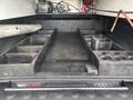 A wooden truck bed slide system with multiple compartments and slots for tools and equipment in the bed of a 2016 RAM 1500