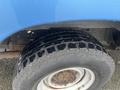 Close-up of a tire from a blue 2009 Ford Econoline showing a rugged tread pattern with some rust on the wheel rim