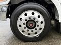 Close-up of a silver wheel and tire from a 2020 Peterbilt 330 showcasing multiple lug nuts and a center hub cap