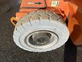 A close-up of a large rubber tire from a 2012 JLG E400AJFN with visible tread patterns and mounted on a metal wheel