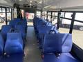 Interior of a 2020 Chevrolet Express showing rows of blue upholstered seats with seatbelts and an open aisle in the center