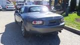A gray 2007 Mazda Miata with a hardtop viewed from the rear showcasing its sleek design and dual exhaust pipes