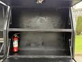 A 2016 Ford F-550 Super Duty truck with an open compartment featuring a fire extinguisher and empty shelves inside