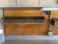 A wooden shelf mounted on a wall with worn edges and chains hanging over the side