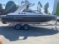 A 2013 Larson 238 boat on a trailer with a sleek design and a prominent wakeboard tower showcasing the name "DISAPPEARING ACT III" on its side