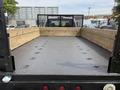 A 2008 Ford F-550 flatbed truck with a black metal surface and wooden side rails