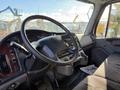 Interior view of a 2012 Freightliner M2 106 featuring a black steering wheel dashboard controls and gray fabric seating