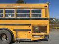 A 2006 Thomas Saf-T-Liner HDX yellow school bus view from the rear showing windows a black stripe and a mesh pattern on the side