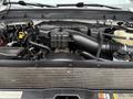Engine compartment of a 2015 Ford F-350 SD featuring a large black engine cover various hoses and fluid reservoirs