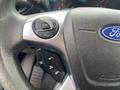Close-up of a Ford steering wheel featuring buttons for cruise control and audio settings with the Ford logo prominently displayed