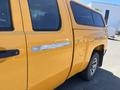 A bright yellow 2013 Chevrolet Silverado 1500 with a black door handle and a truck bed cap, showing some signs of wear on the side panel