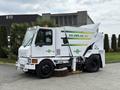 A white 2012 Global M4 street sweeper with a front-mounted broom and green and yellow branding on the side