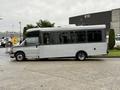 A 2020 Chevrolet Express shuttle bus with a large windows and a raised roof parked beside a building