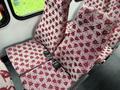 Two red and white patterned seats with seat belts inside a 2015 Ford Econoline van