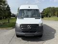 Front view of a 2023 Mercedes-Benz Sprinter van featuring a gray lower section and a white upper body with the iconic three-pointed star logo on the grille