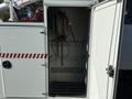 A 2010 International 4300 vehicle with an open side compartment showcasing a hose reel and interior shelving