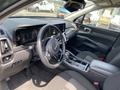 Interior of a 2022 Kia Sorento featuring a modern dashboard with a digital display and a sleek steering wheel along with black leather seats and a console between the front seats