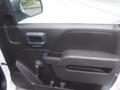The interior door panel of a 2015 Chevrolet Silverado 1500 with a black plastic handle and armrest