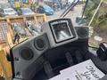 Interior view of a 2012 Caterpillar 980 featuring a display panel with gauges and controls along with two speakers and a workspace area with papers and a clipboard