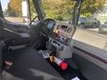 Interior of a 2022 Freightliner M2 106 featuring dashboard controls steering wheel and a seat with a fire extinguisher on the floor