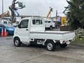 A white 2008 Suzuki Carry mini truck with a flatbed and cab design viewed from the rear and side