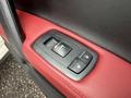 A close-up of the window and door lock controls of a 2016 Maserati Ghibli featuring a black and red interior design