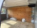 Interior of a 2013 Ford Econoline cargo van featuring a wooden panel along the back wall and a flat wooden floor with two curved wheel wells visible